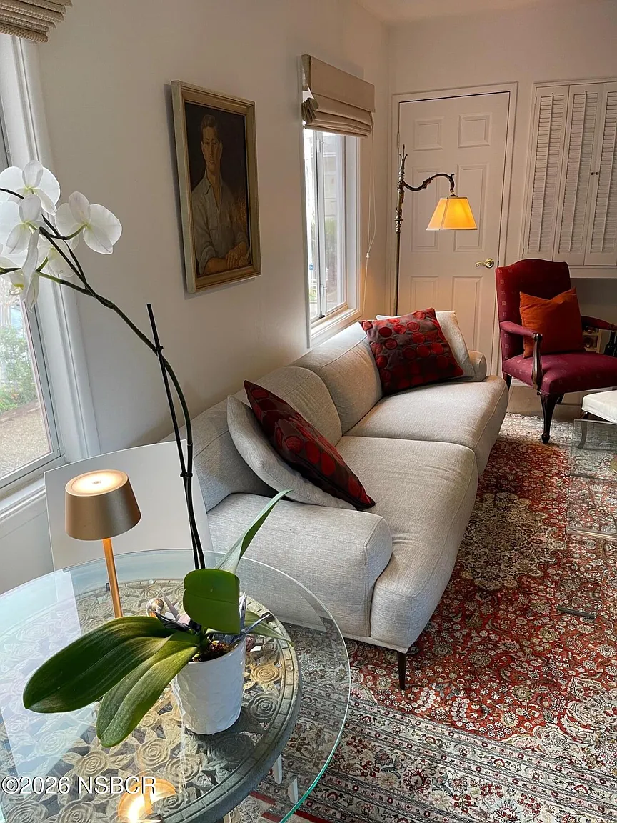 Designed with a Persian-style area rug that lies beneath a light-colored sofa and glass-topped tables.