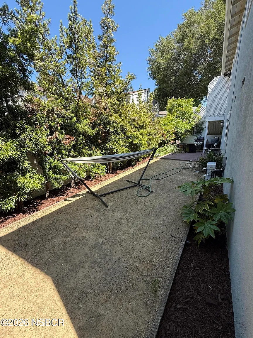 Another private yard offers a more secluded space with decomposed granite ground cover bordered by mature shrubs and trees.