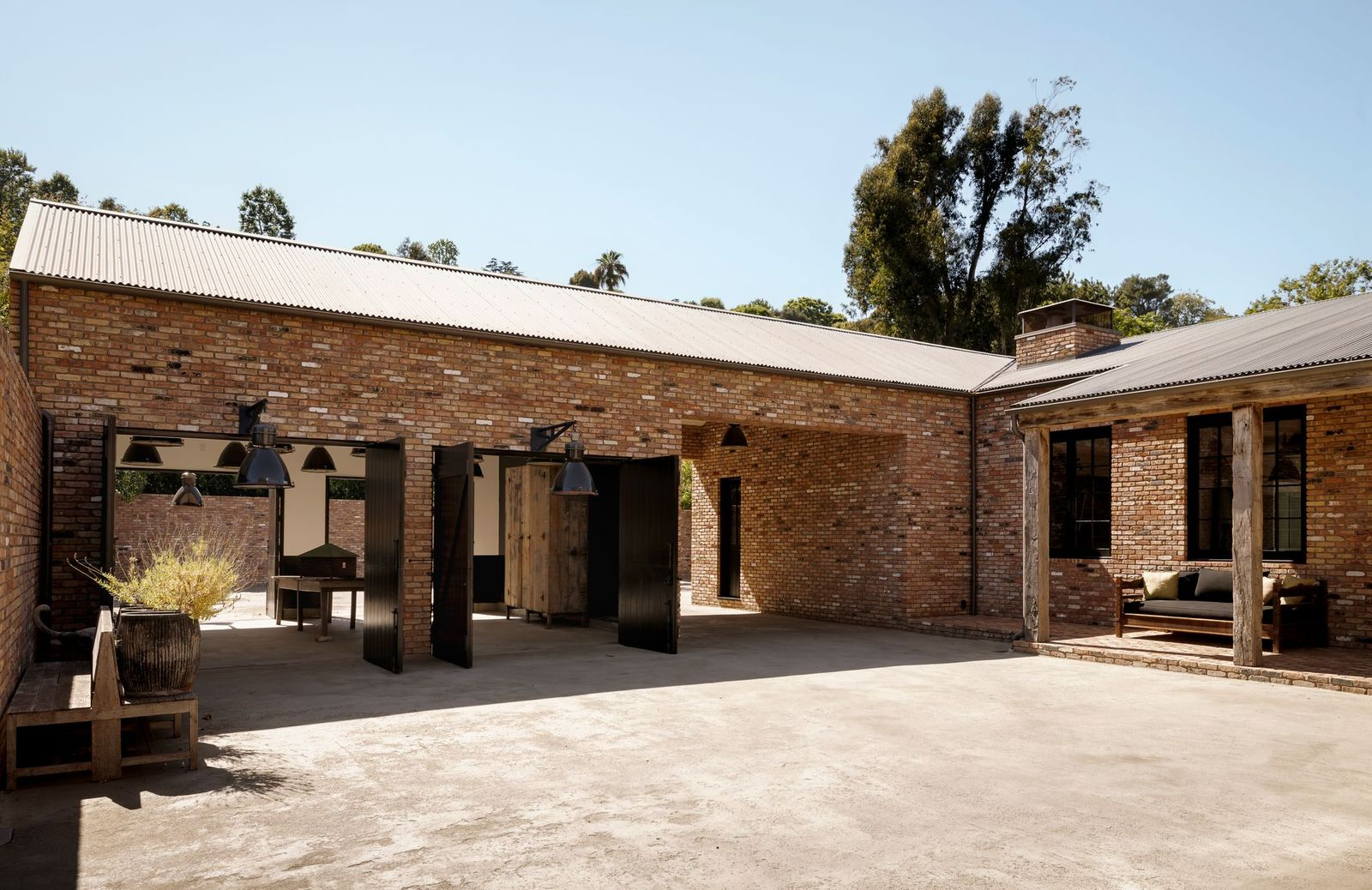 The courtyard connects to the expansive motor court through large openings in the structure that lead directly through the house, where another set of gates frames the opposite end of the property.