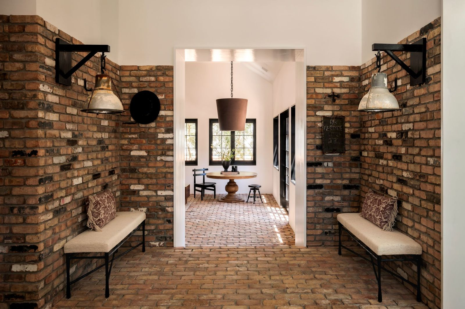 A pair of vintage-style metal light fixtures hang overhead, while benches create a simple seating area along either side of the space.