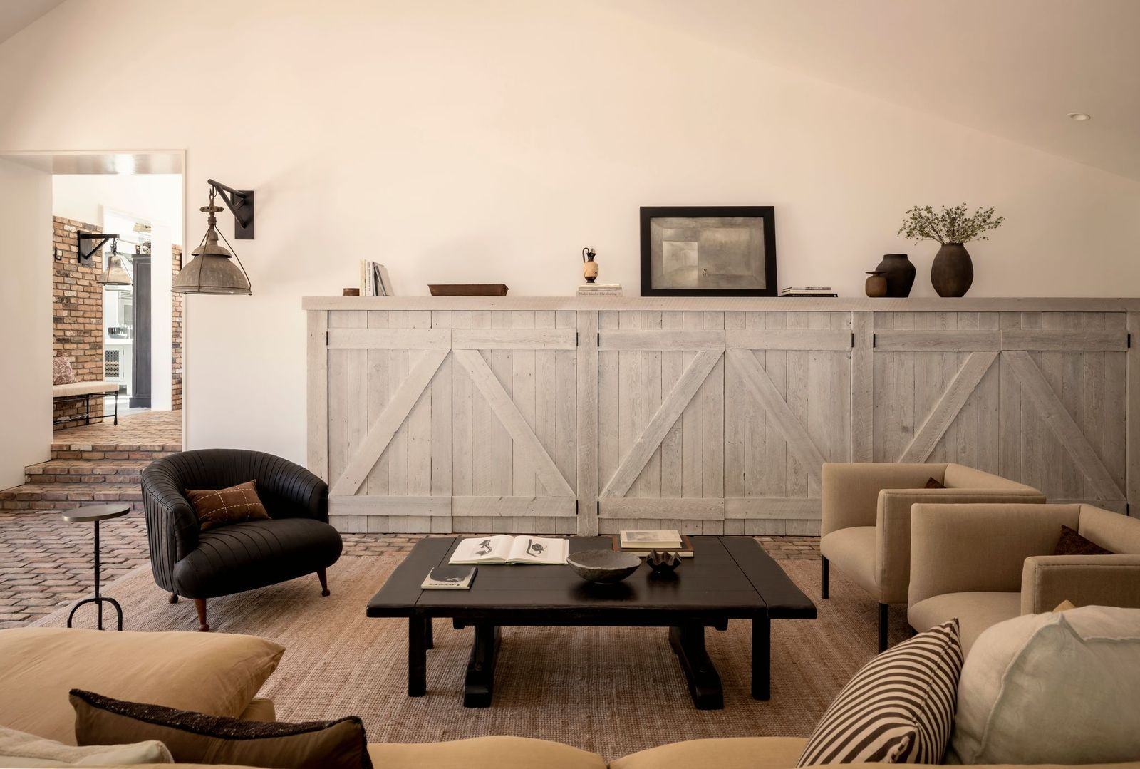 Neutral furnishings, including low-profile sofas, sculptural lounge chairs, and a dark wood coffee table, keep the focus on the architecture and materials.