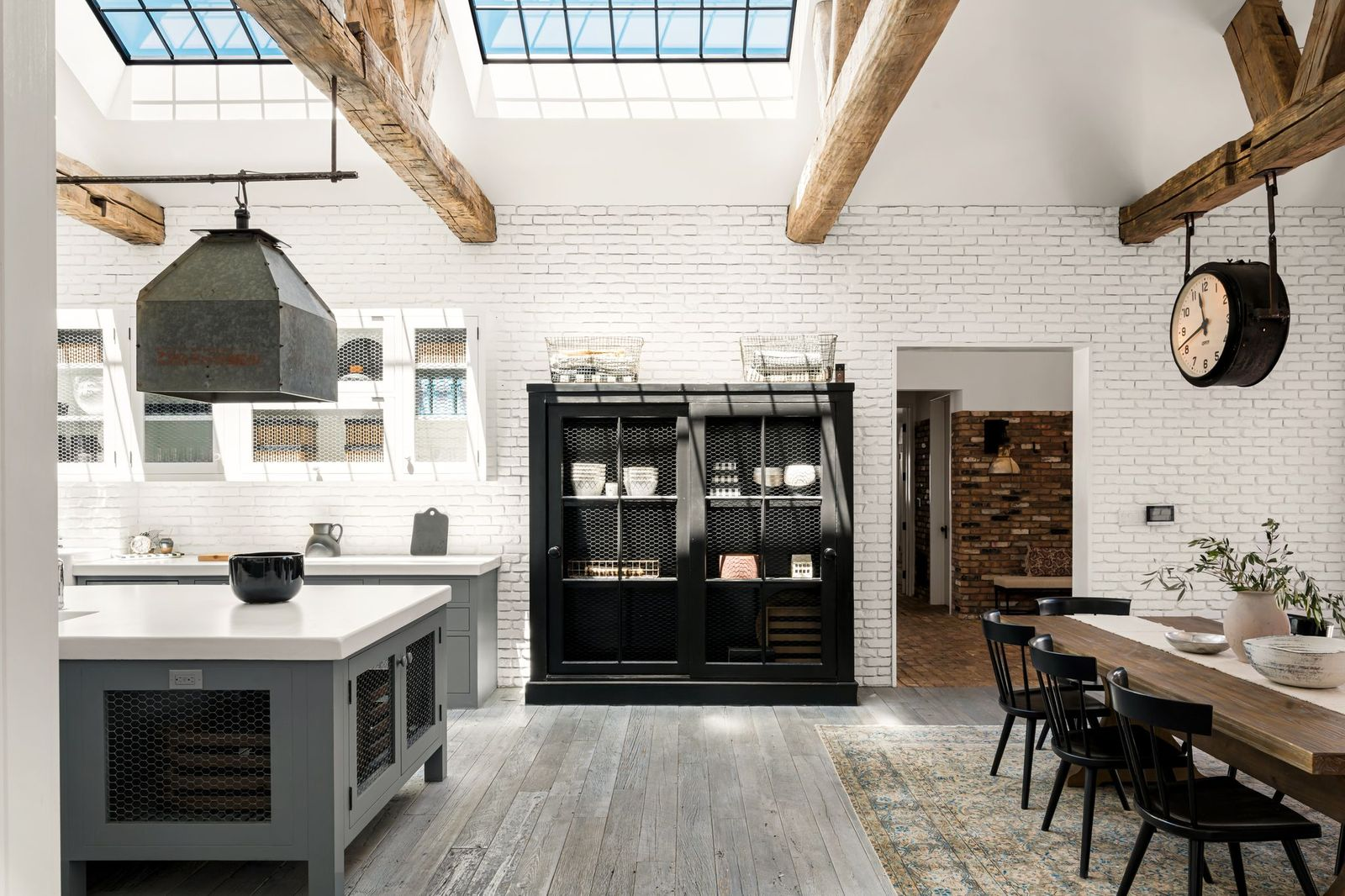 White-painted brick walls, black steel accents, and wide-plank flooring create a palette that feels both industrial and farmhouse-inspired.