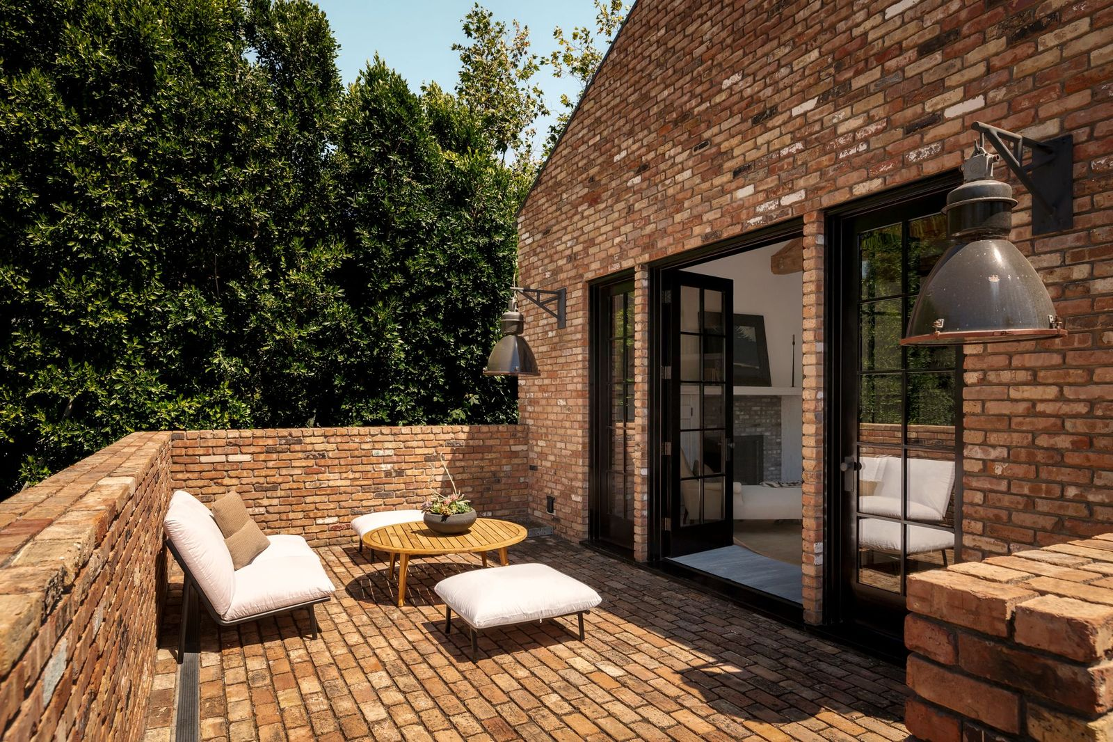 Just outside the bedroom, a brick terrace creates a secluded outdoor sitting area with matching lounge seating and a small table.