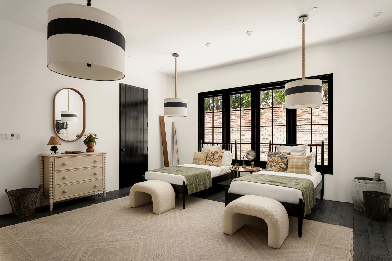 Designed to accommodate multiple guests, this bedroom features a pair of twin beds positioned beneath oversized pendant lights suspended from thick rope cords.