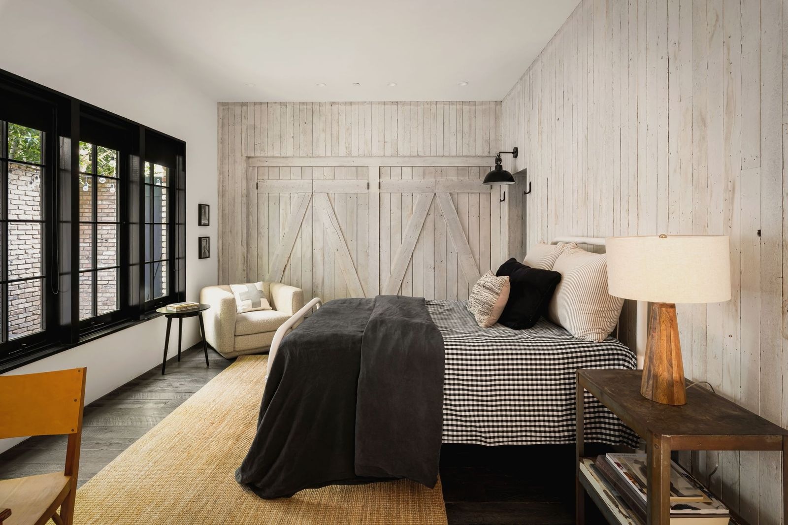Whitewashed plank walls extending from floor to ceiling and oversized sliding barn-style doors that conceal storage along one wall.