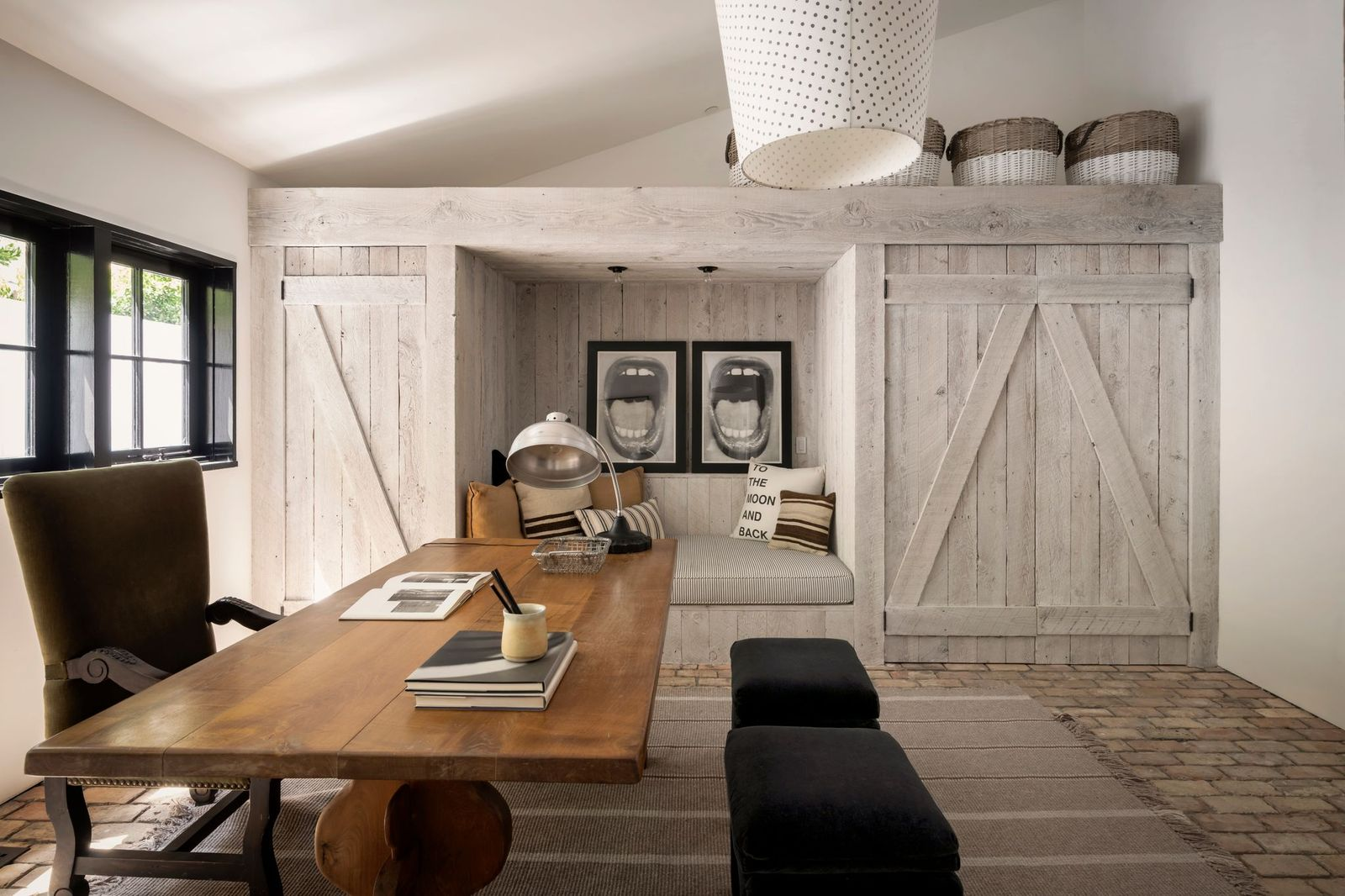The primary office features a large wood desk positioned beside black-framed windows that bring in natural light throughout the day.