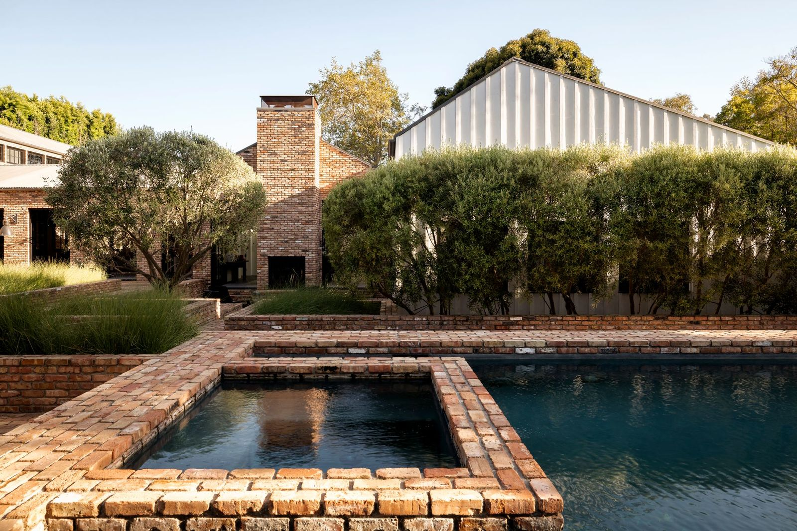 The raised spa sits at one end of the pool and is connected by a series of narrow brick walkways that extend across the water.