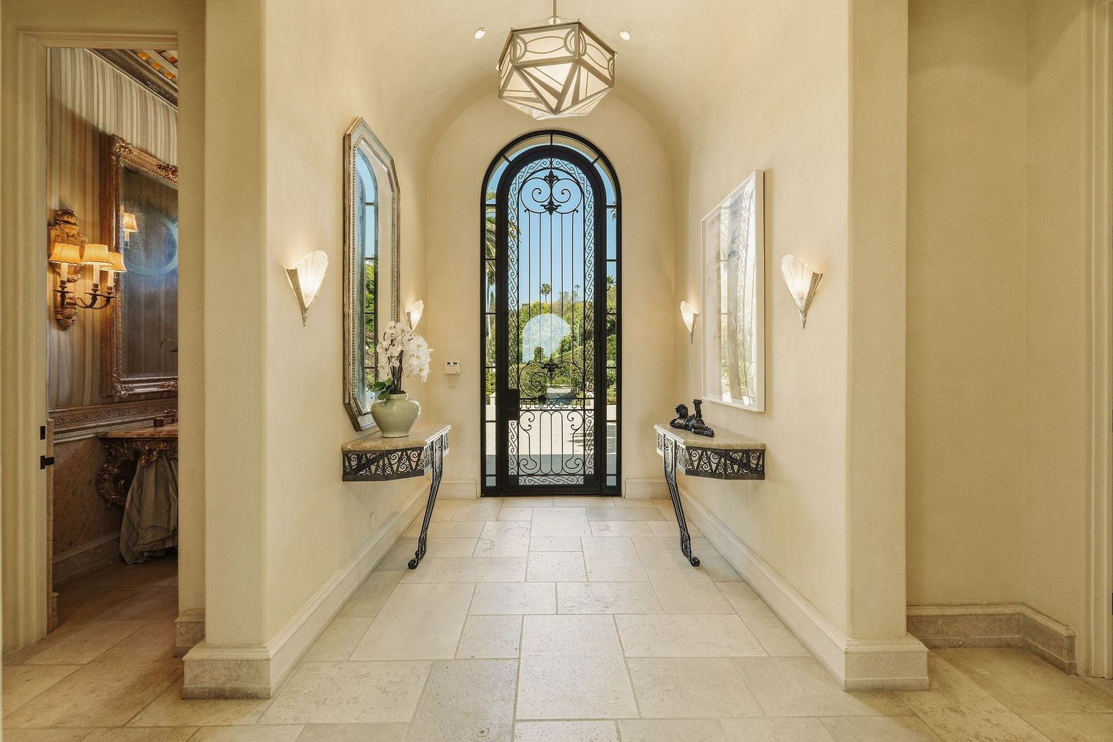 A long gallery-style foyer finished with creamy Venetian plaster walls, limestone flooring, and soaring barrel-vaulted ceilings. 