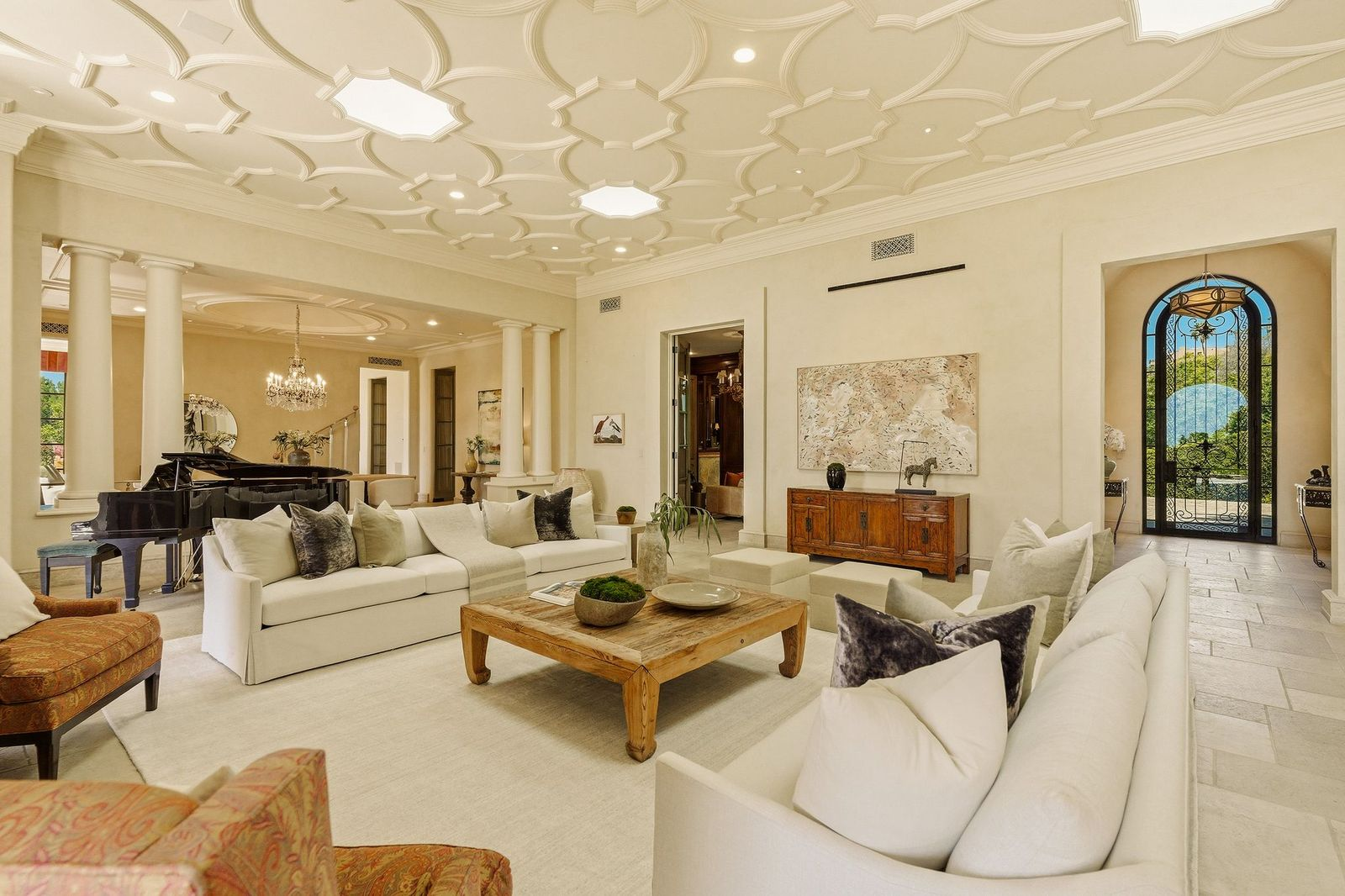 The open layout extends toward a grand piano and adjoining reception space framed by classical columns.