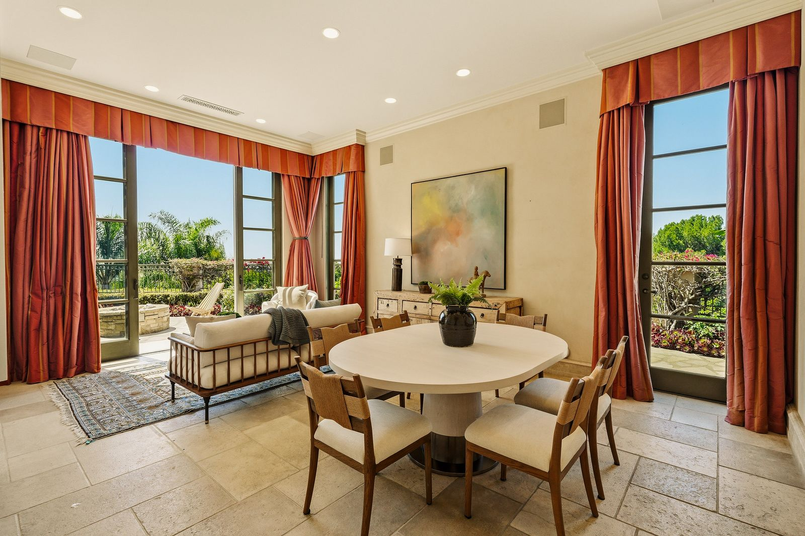 Inside, a round dining table sits at the center of the room, while a small sitting area beside the French doors creates a comfortable spot to enjoy the outdoor views.