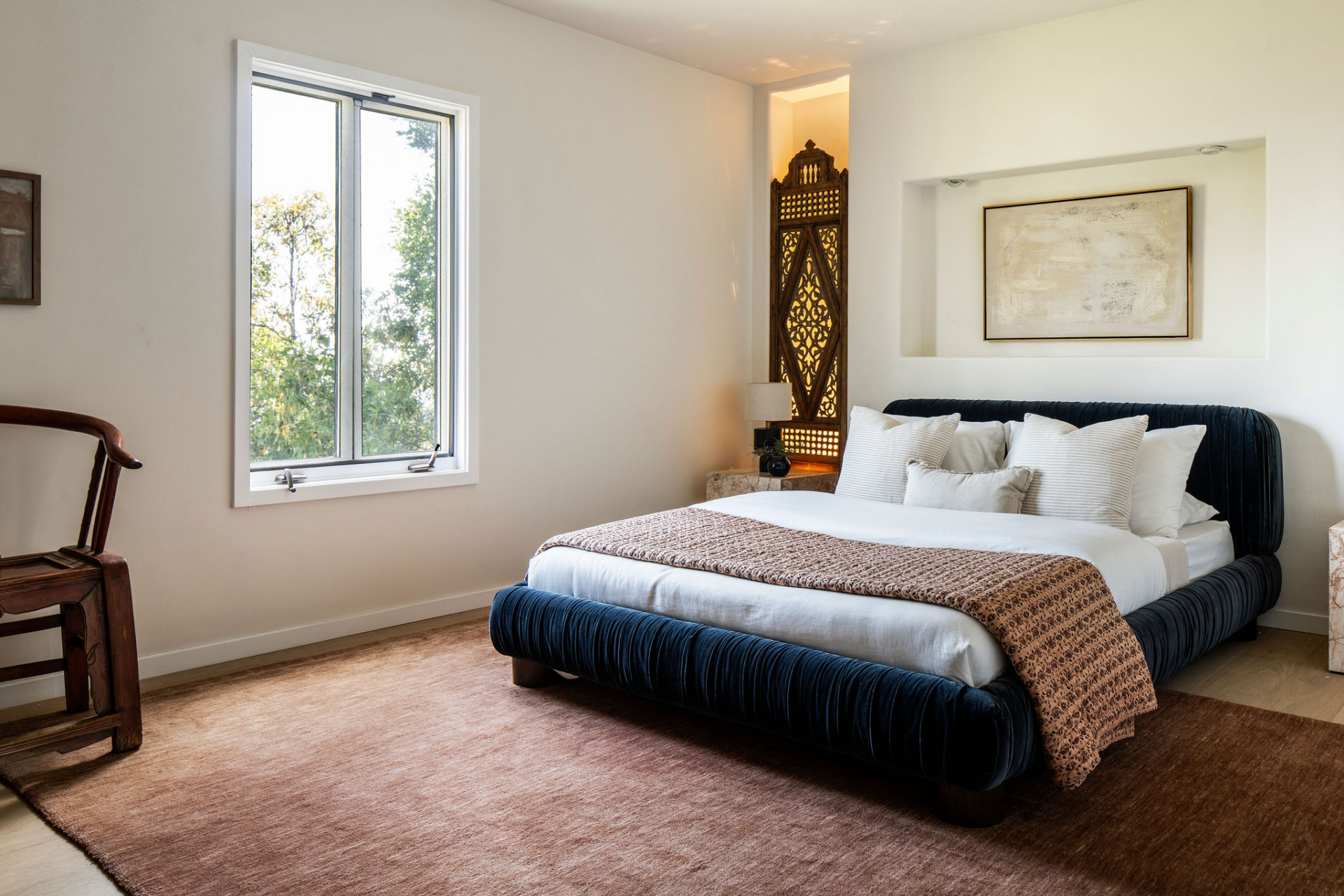 Defined by its deep blue velvet bed frame, this bedroom offers a more dramatic take on the home's more restrained palette. 