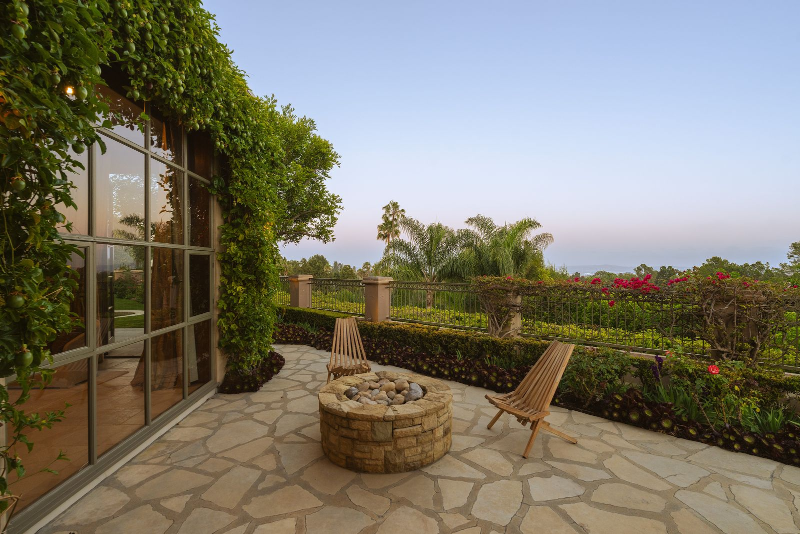 In a secluded corner of the estate sits a stone terrace centered around an open-air fire pit with sweeping views across the surrounding landscape.