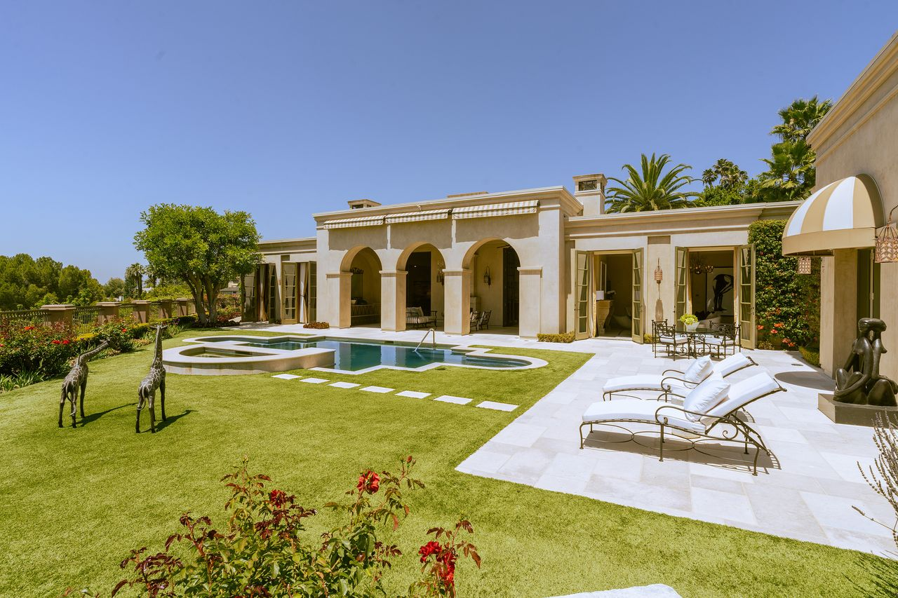 A freeform pool and raised spa are surrounded by expansive lawns, while French doors from several rooms offer an easy flow between the interiors and the landscaped backyard.