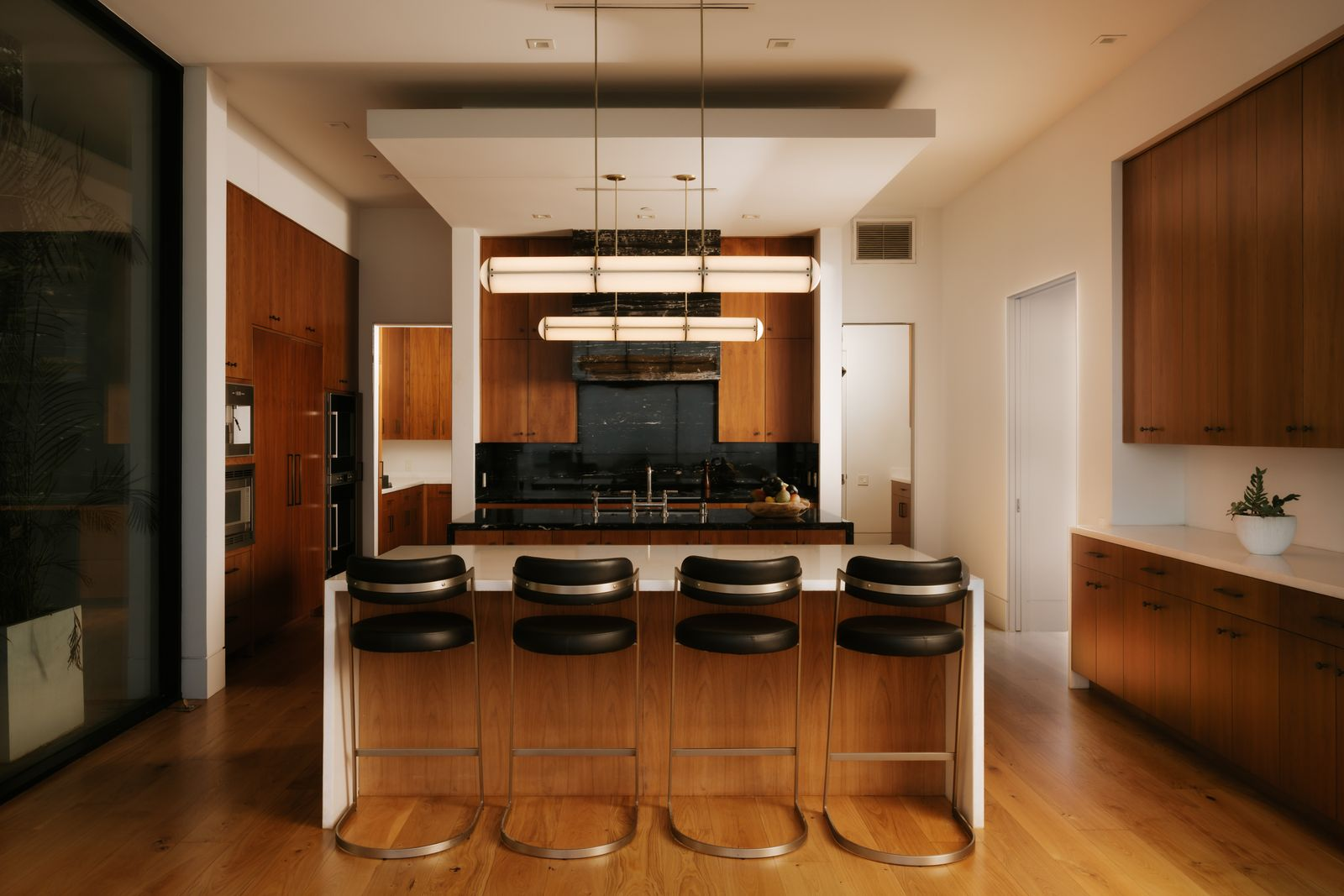 Warm walnut cabinetry is paired with marble countertops and a dramatic black stone backsplash.