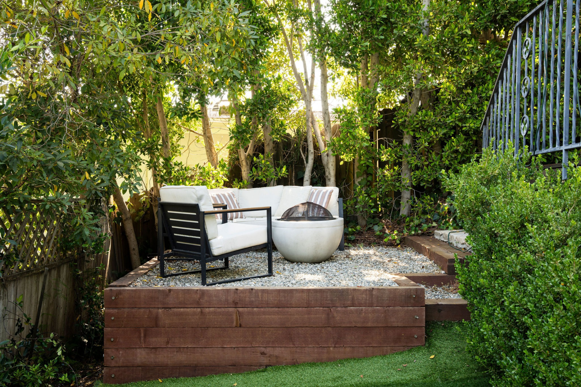 The raised gravel seating area creates a quiet corner of the property, with seating arranged around a modern fire feature and surrounded by natural privacy.