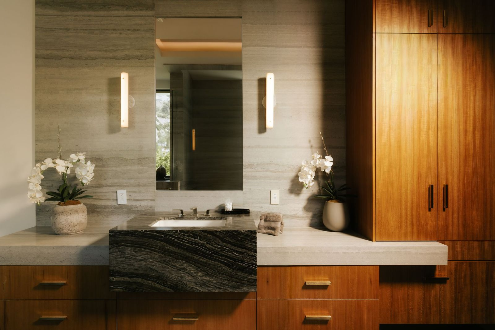 One of the two bathrooms combines walnut cabinetry with dramatic stone surfaces, including a vanity topped with richly veined marble. 