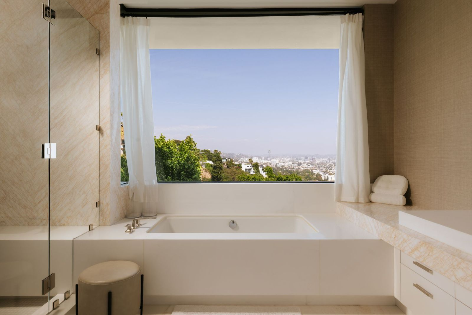 A deep soaking tub positioned beneath an oversized picture window overlooking the skyline. 