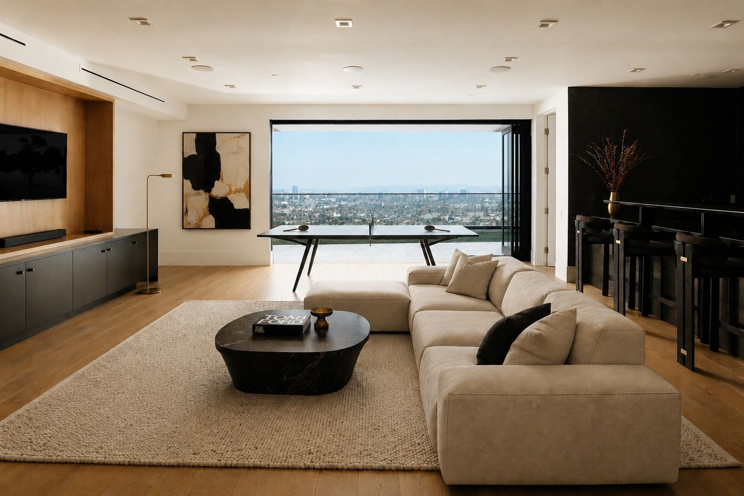 At the center of the level is a spacious lounge where a large sectional faces a built-in media wall and a ping pong table is positioned in front of retractable glass doors that open to another terrace. 