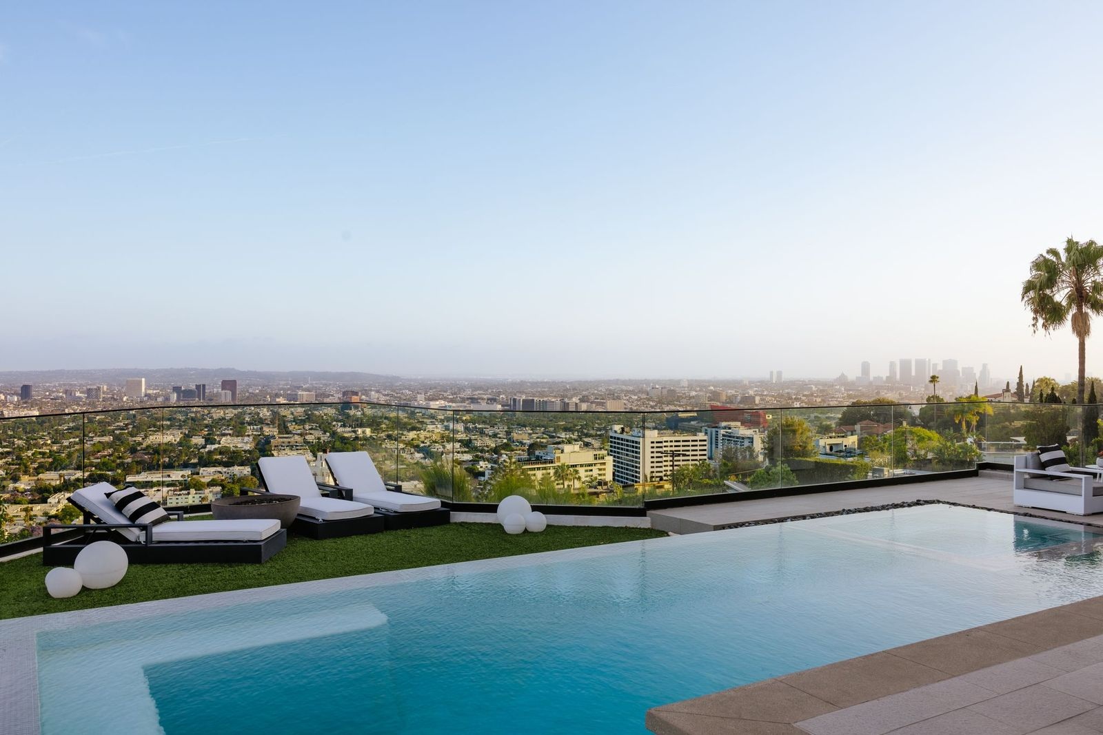 Glass railings along the edge of the backyard preserve uninterrupted sightlines, while lounge chairs, conversation areas, and generous deck space provide multiple places to relax around the water.