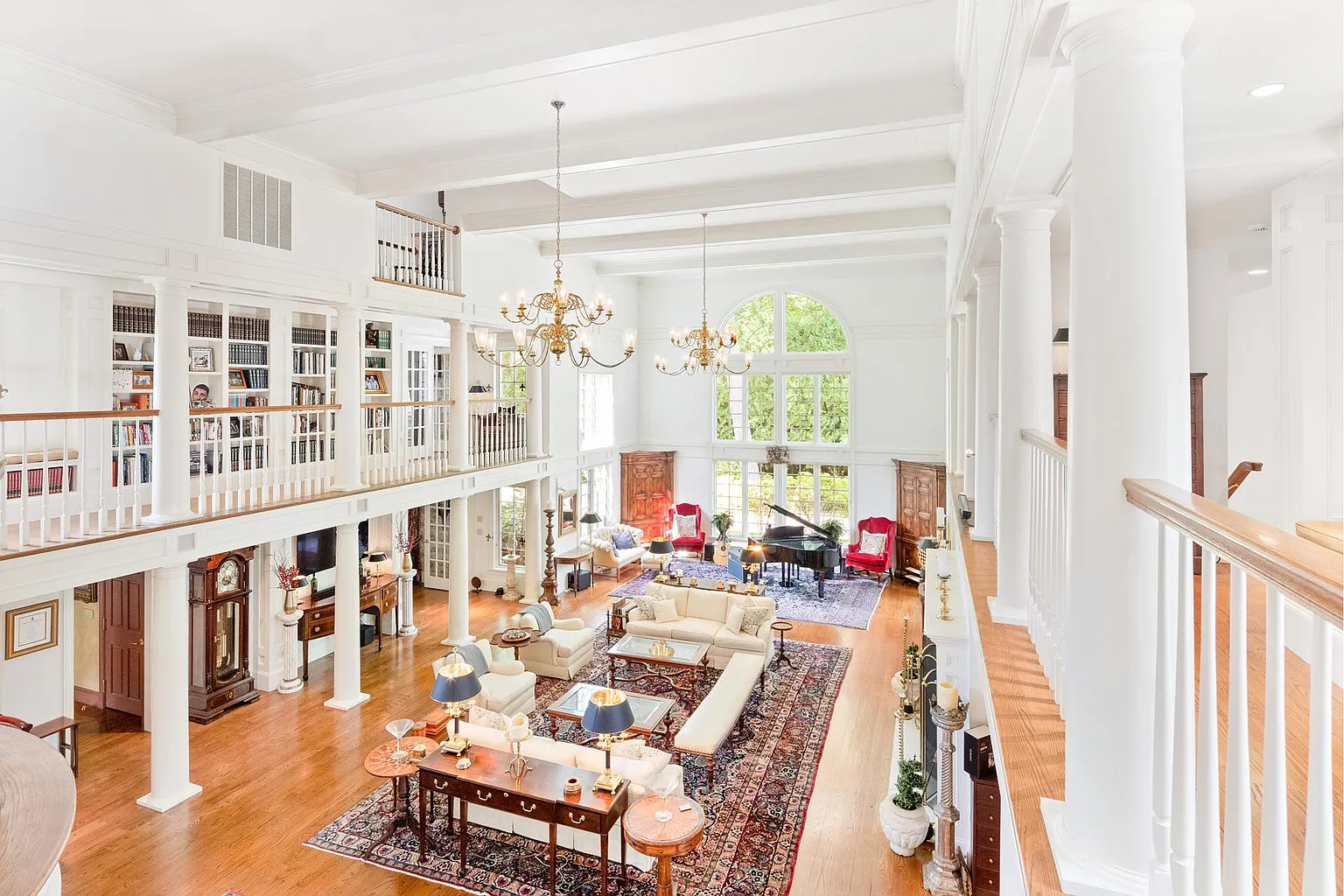 The great room opens directly into the formal dining room, with built-in bookcases and upper-level balconies reinforcing the home's grand design.