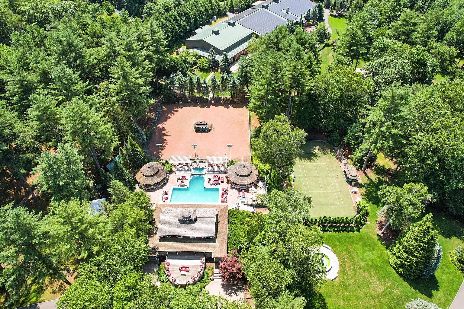 Aerial view of the pool area, tennis court, and spa building.