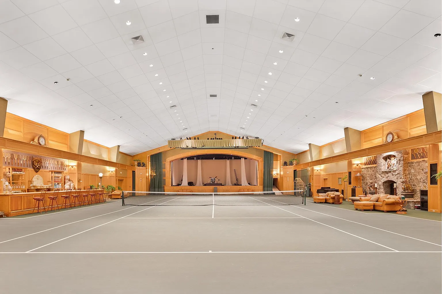 In addition to a full-size indoor tennis court, the venue features a full bar, multiple lounge areas, and a massive stone fireplace.