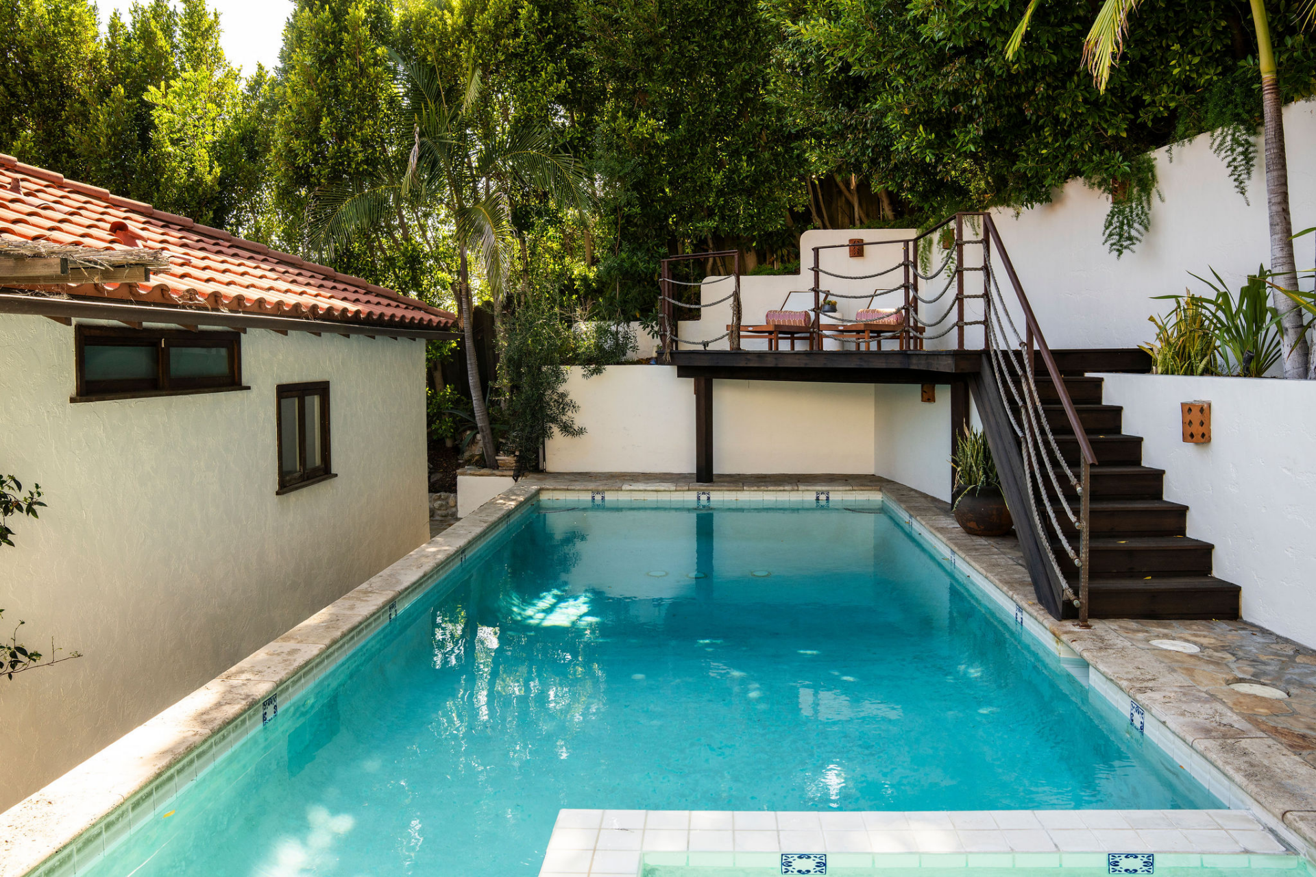The courtyard's centerpiece is a rectangular pool and spa framed by white stucco walls and lush landscaping. 