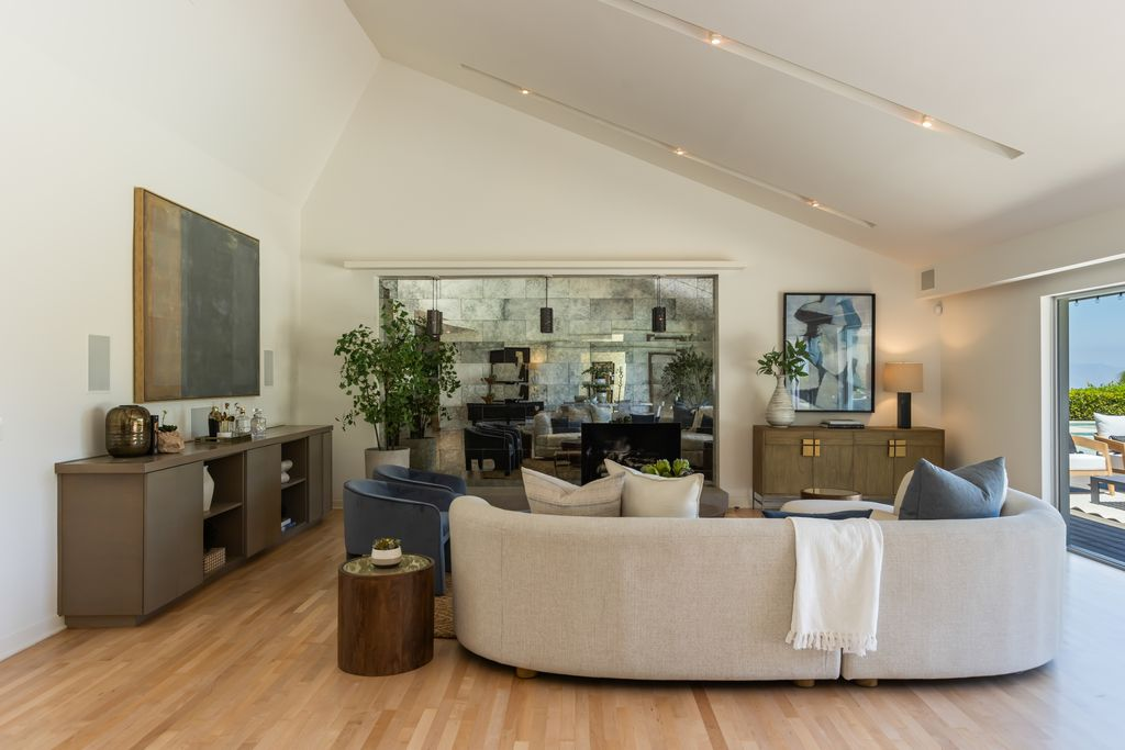 The living room centers around a sleek fireplace of textured stone, creating a natural focal point.