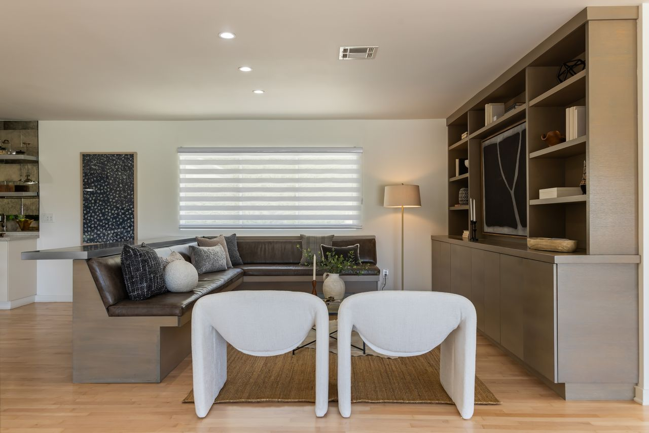 Built-in cabinetry with a TV lining the wall across from a wraparound leather banquette seat.