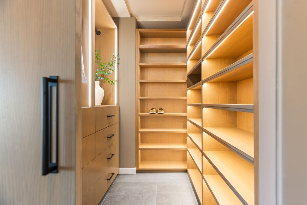 Closet with floor-to-ceiling shelving, integrated drawers, and LED-lit cabinetry.