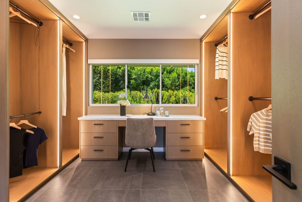 Walk-in closet arranged around a built-in vanity beneath a large window.