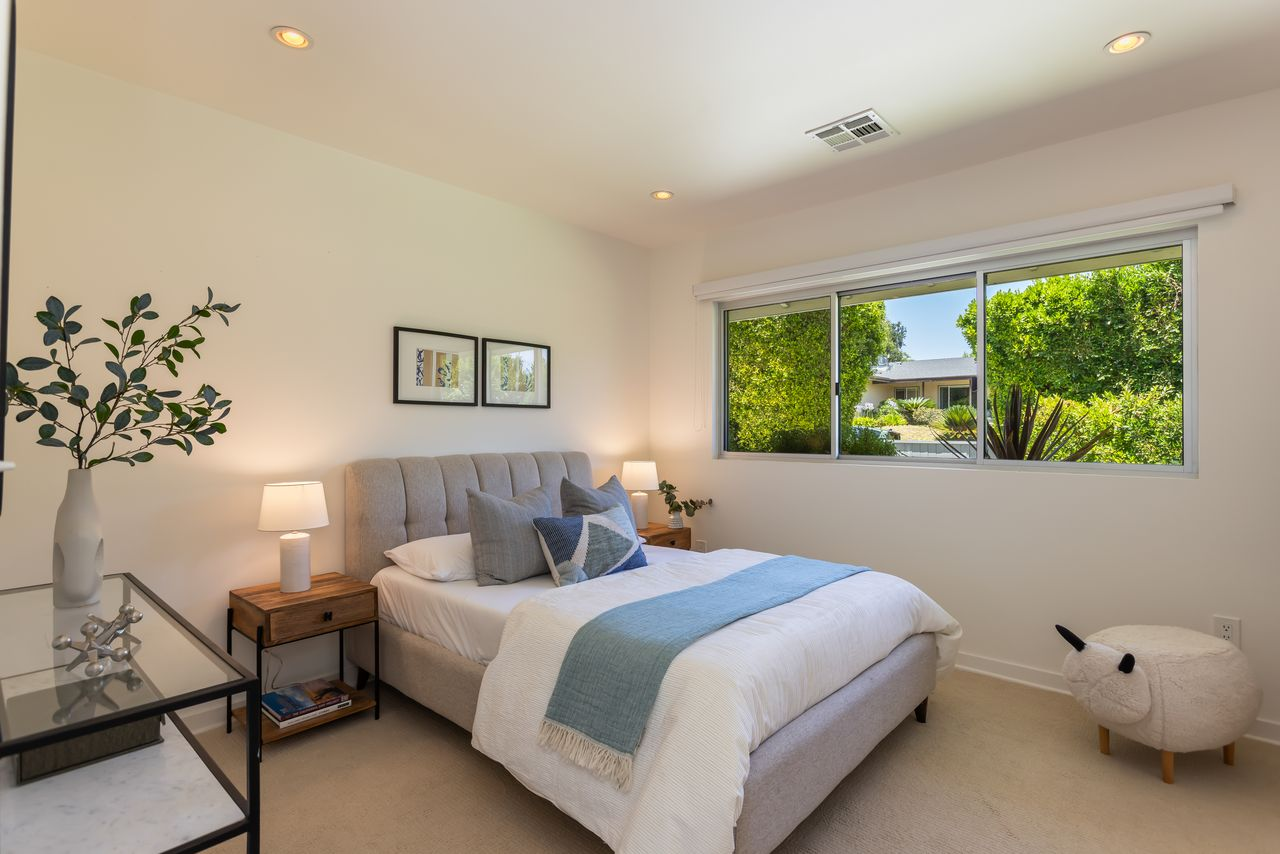 A tufted upholstered bed is paired with simple wood nightstands and neutral furnishings.
