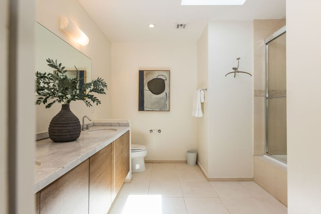 Bathroom with a marble-topped vanity, a combination soaking tub and shower, and a skylight that brightens the space throughout the day.