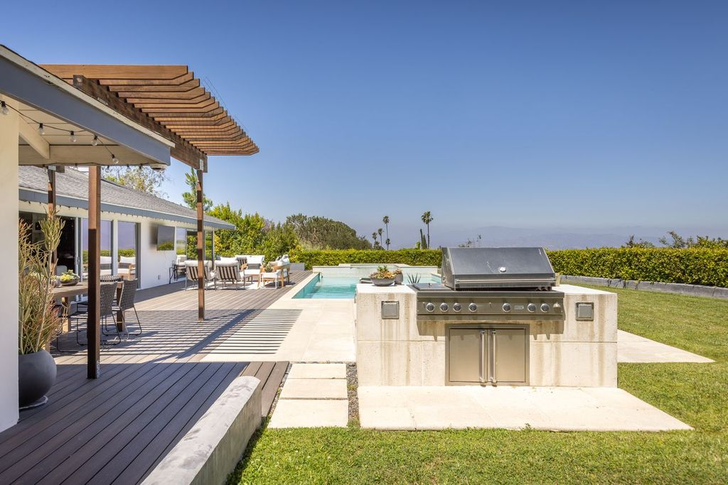 Positioned just off the main deck is a built-in outdoor kitchen featuring a stainless steel grill set into a concrete surround.