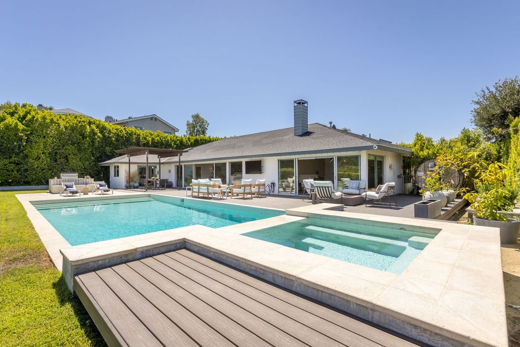 The centerpiece of the backyard is a rectangular swimming pool paired with an elevated spa that spills over into the water below. 