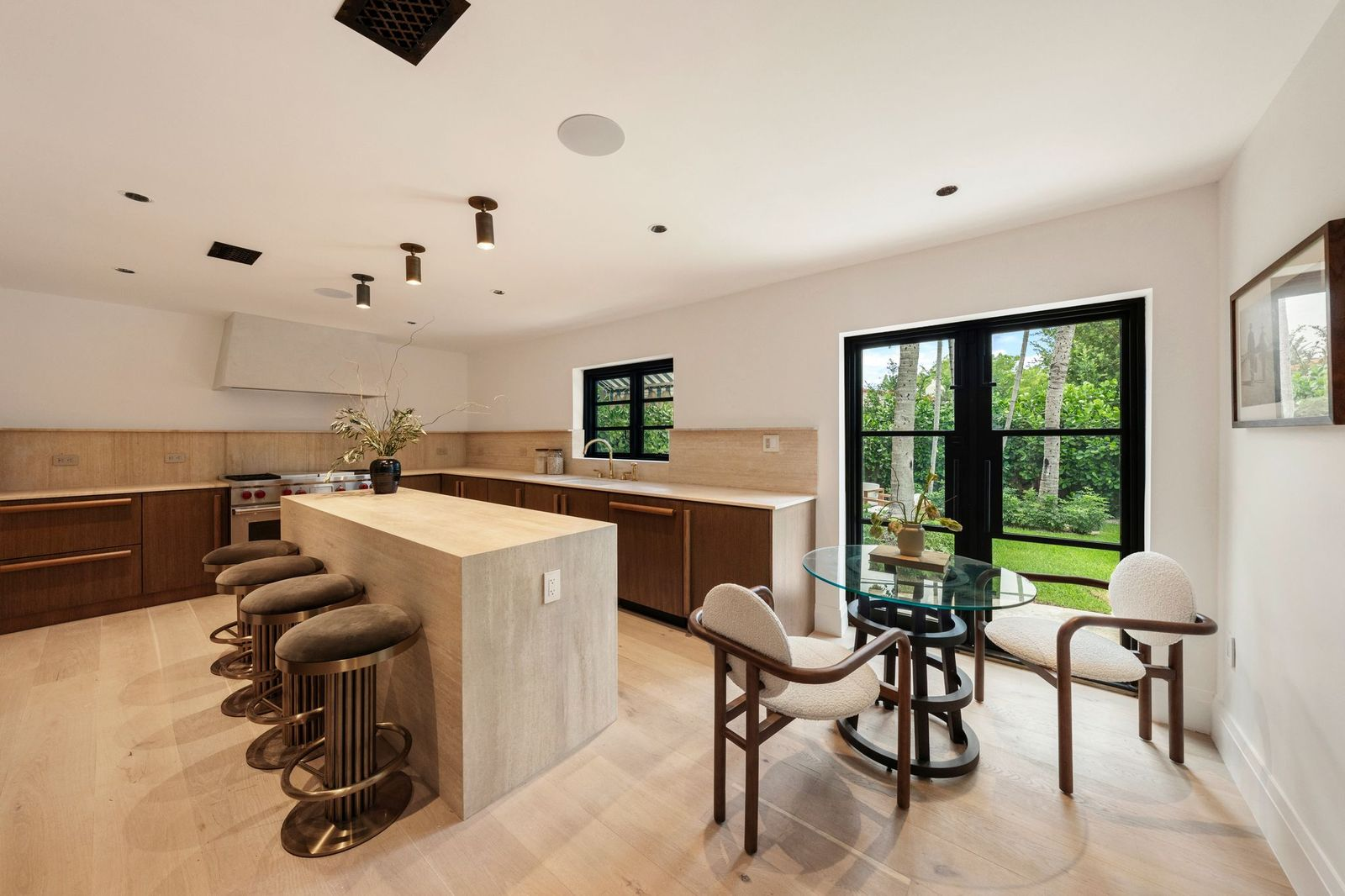 The kitchen pairs white oak finishes with light stone surfaces and streamlined detailing. 