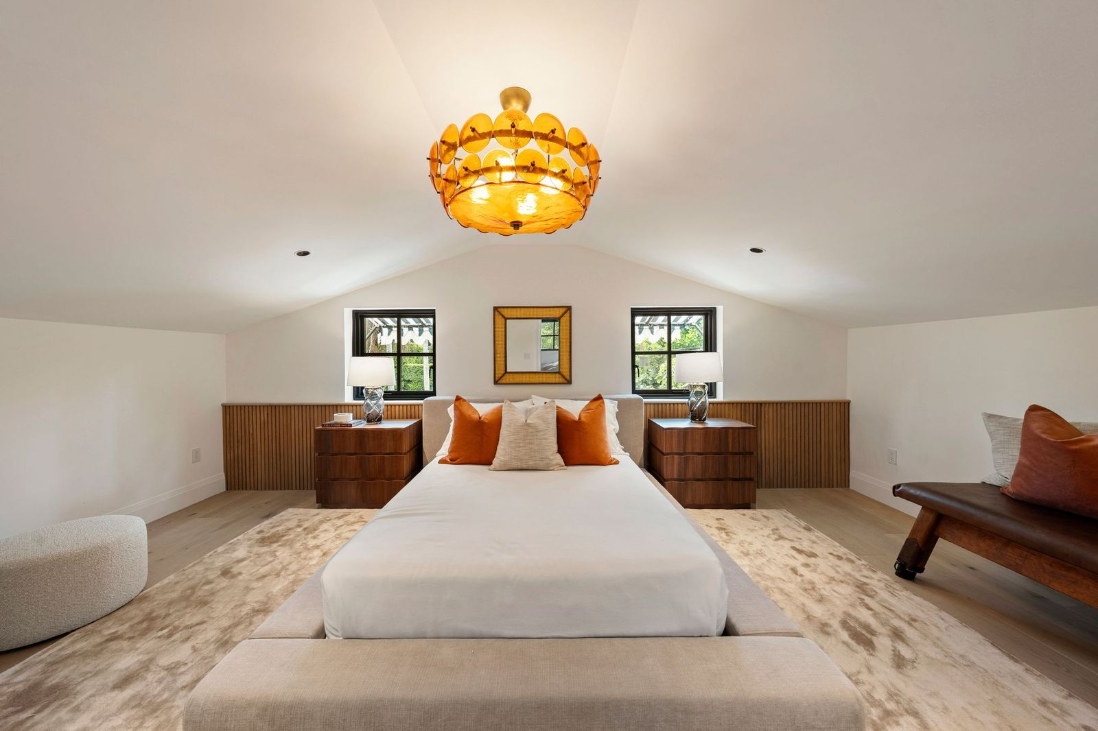 Matching black-trimmed windows sit on either side of the bed, while continuous wood paneling wraps the lower walls behind the headboard and nightstands. 