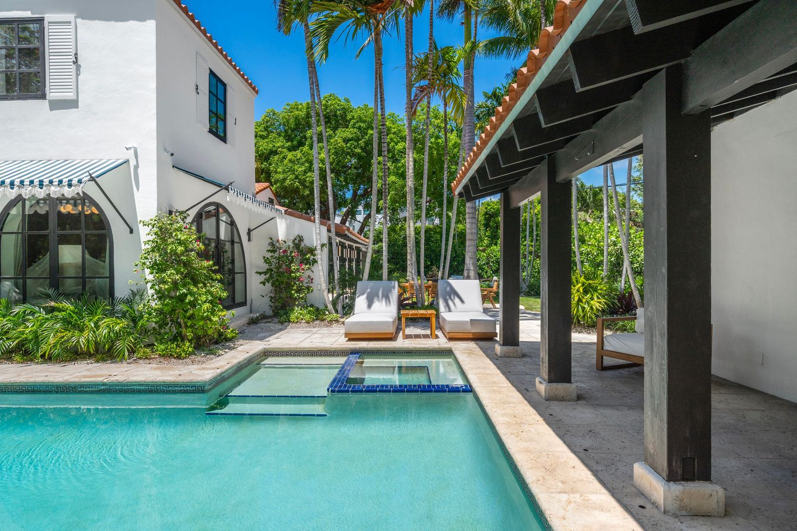 A rectangular swimming pool is paired with an elevated spa finished with blue tile detailing. 