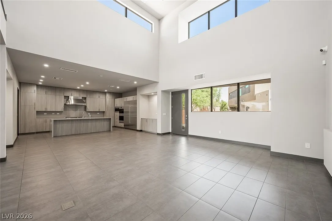 Stepping inside, the home opens to a dramatic double-height great room with soaring ceilings and oversized windows.