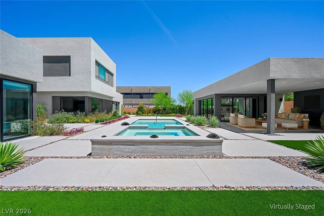 At the center of the backyard, a rectangular swimming pool and raised spa sit within wide concrete walkways that frame the water.