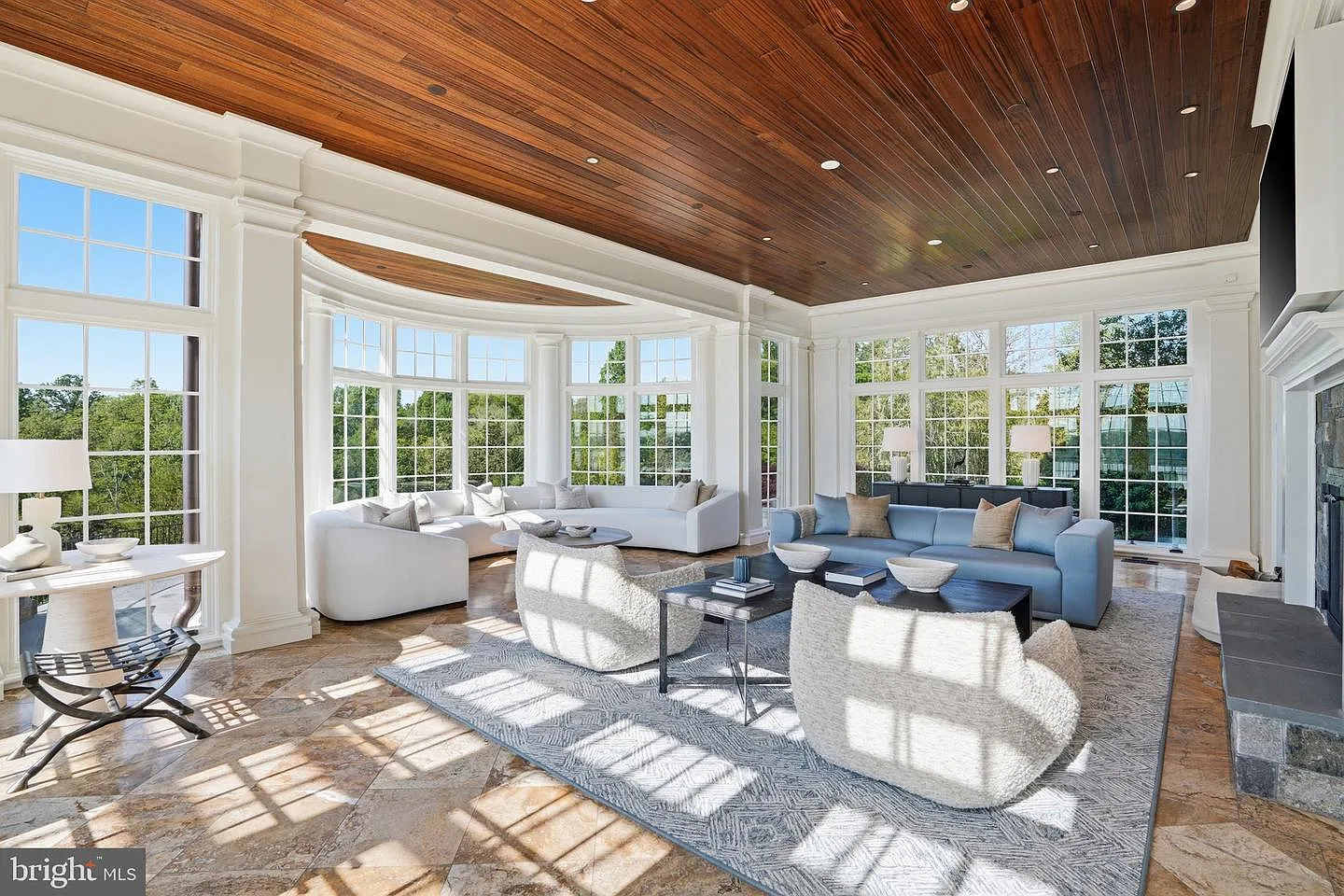 White millwork and classical columns frame the room, while a warm wood-paneled ceiling adds contrast overhead. 