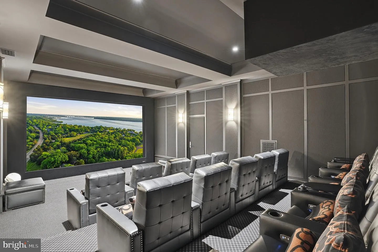 Dark acoustic wall treatments, tiered seating, and dedicated theater chairs create an environment designed specifically for movie nights