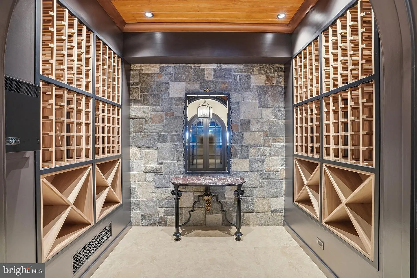 Floor-to-ceiling bottle racks line both sides of the room, while stone accent walls and wood ceilings give the space the appearance of a traditional tasting cellar.