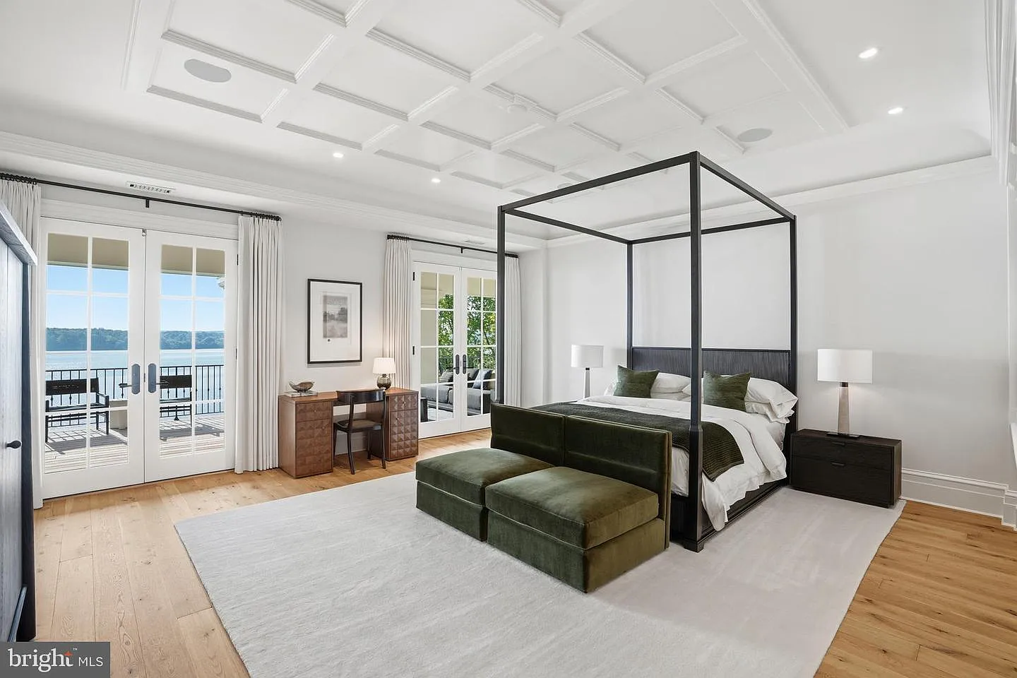 In its own corner of the main residence, the primary suite's bedroom is centered around a four-poster bed beneath a coffered ceiling.