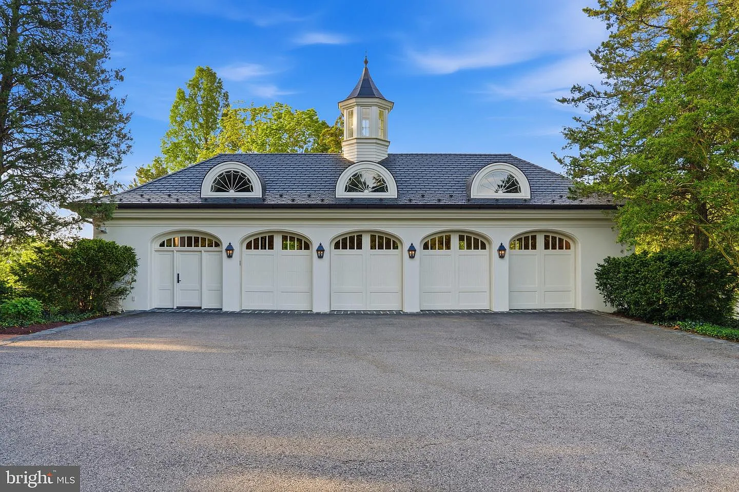 Near the arrival court sits the estate's carriage house, which includes a row of four arched garage doors and a studio apartment above.