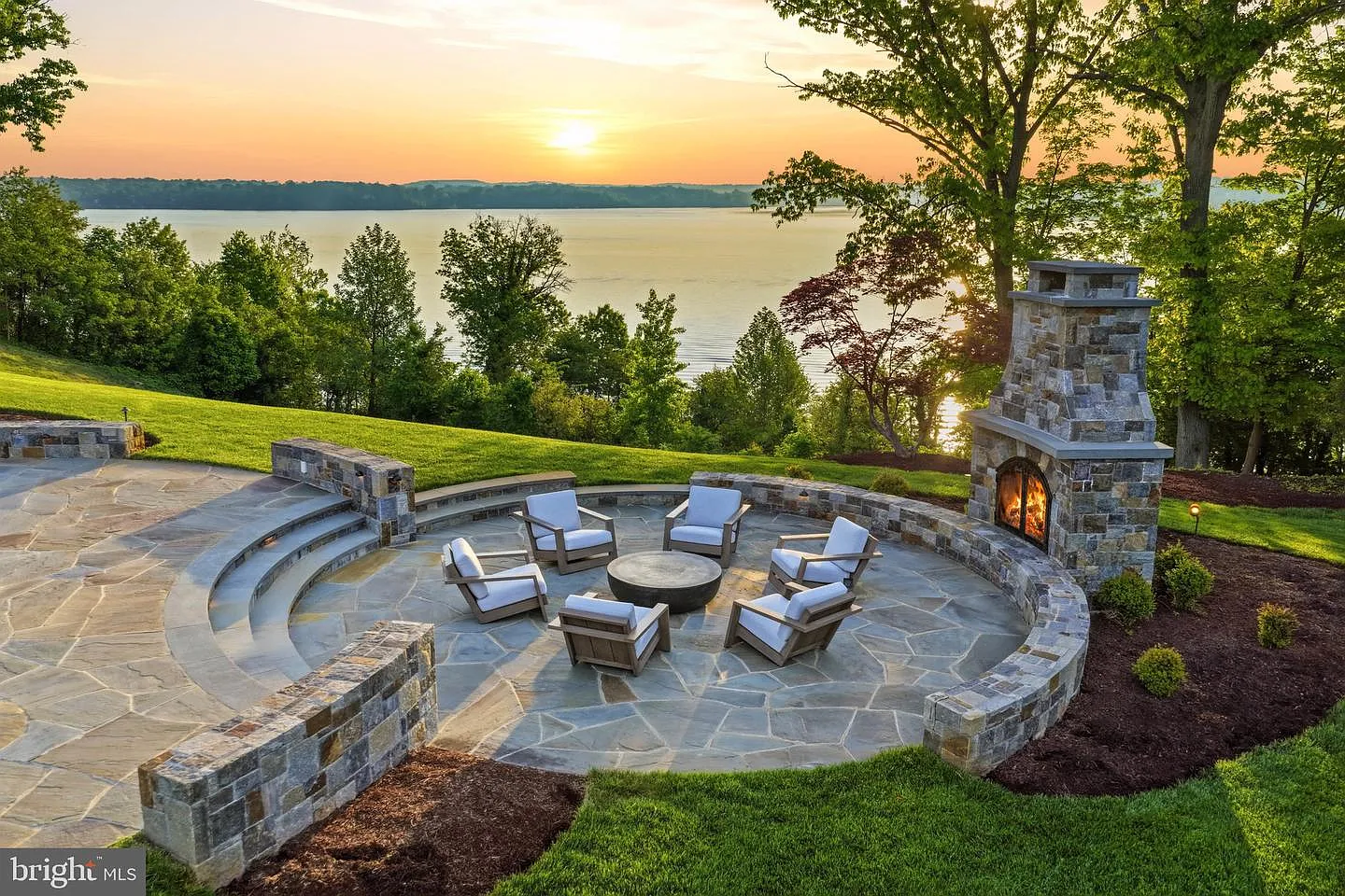 Positioned along the bluff overlooking the Potomac, a stone terrace steps down into a circular fireside lounge centered around an outdoor fireplace.