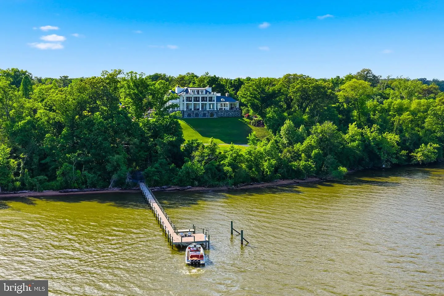 The long pier stretches from the base of the property through the shoreline and into deeper water.