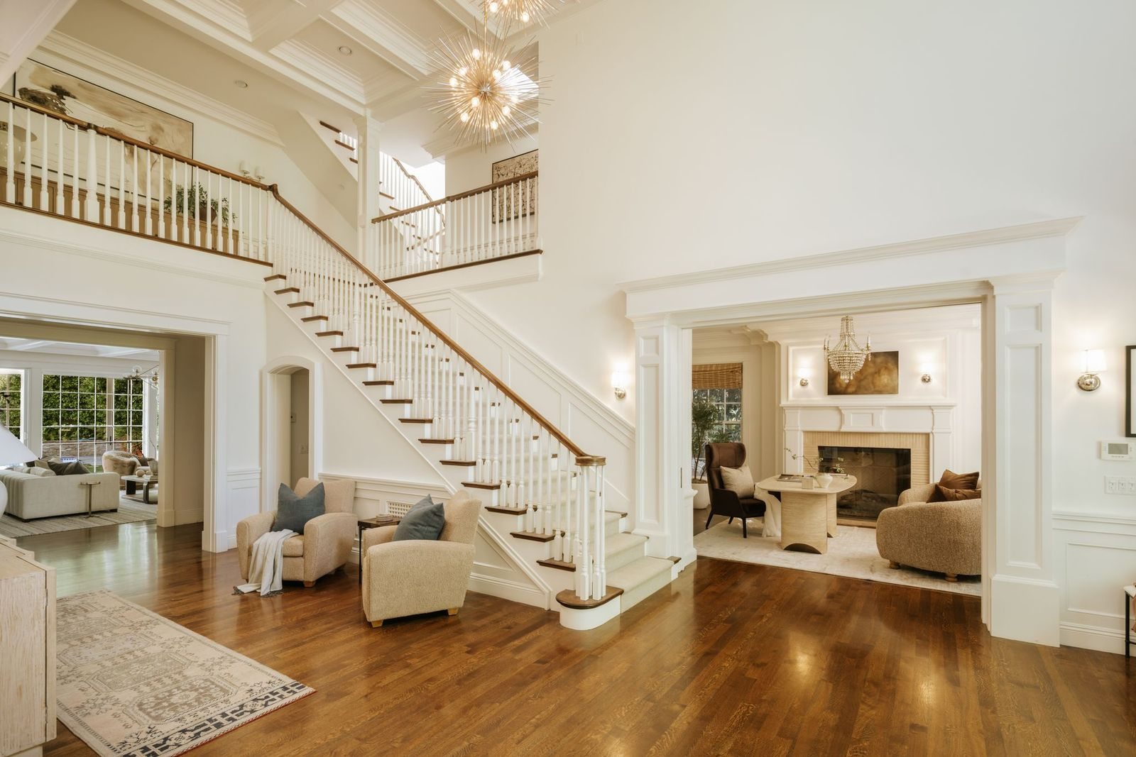 Stepping inside, the home opens with a soaring double-height foyer, where a sweeping staircase, coffered ceilings, and oversized windows set the tone for the rest of the residence. 