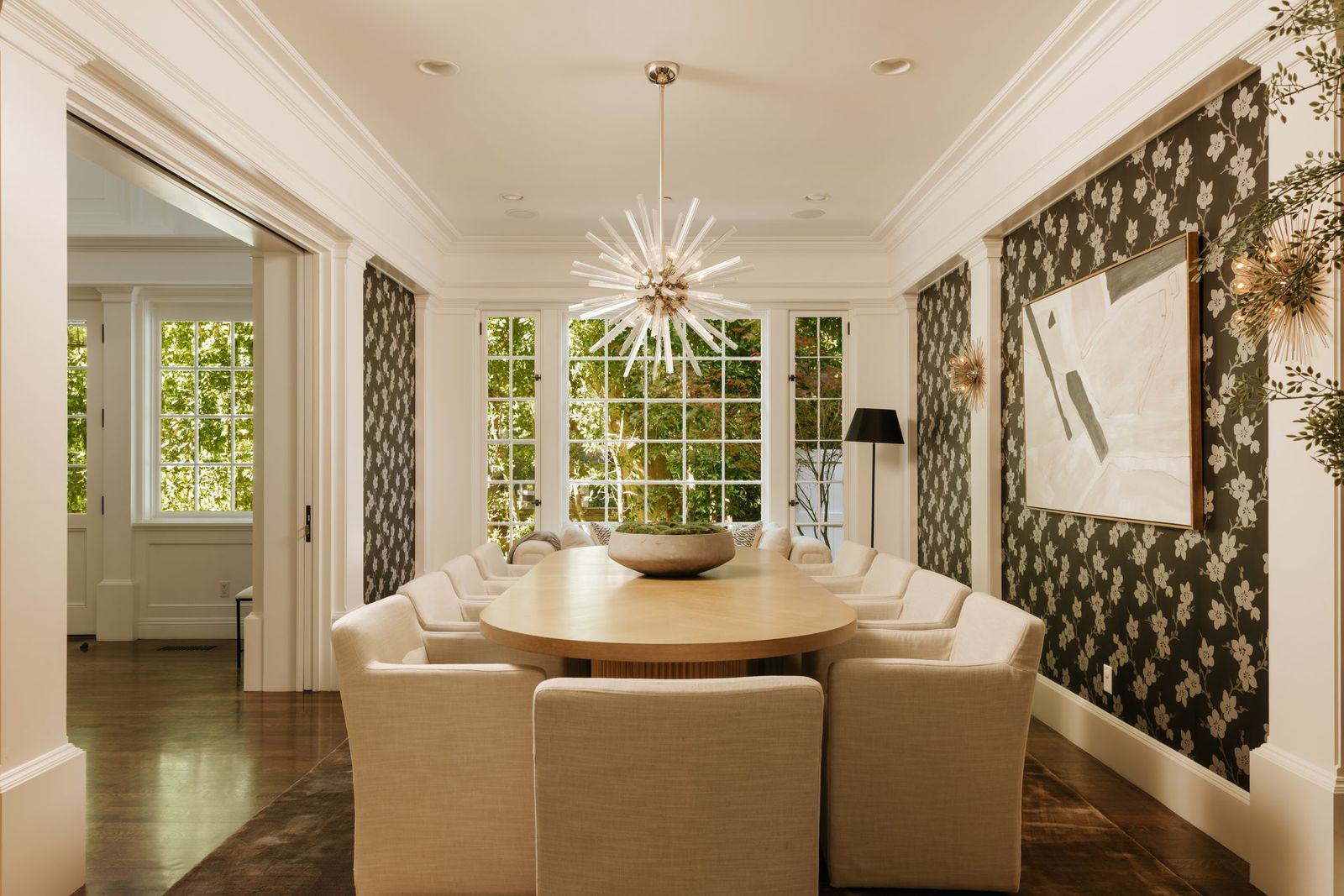 Opposite the office, the formal dining room features a long dining table beneath a sculptural starburst chandelier.