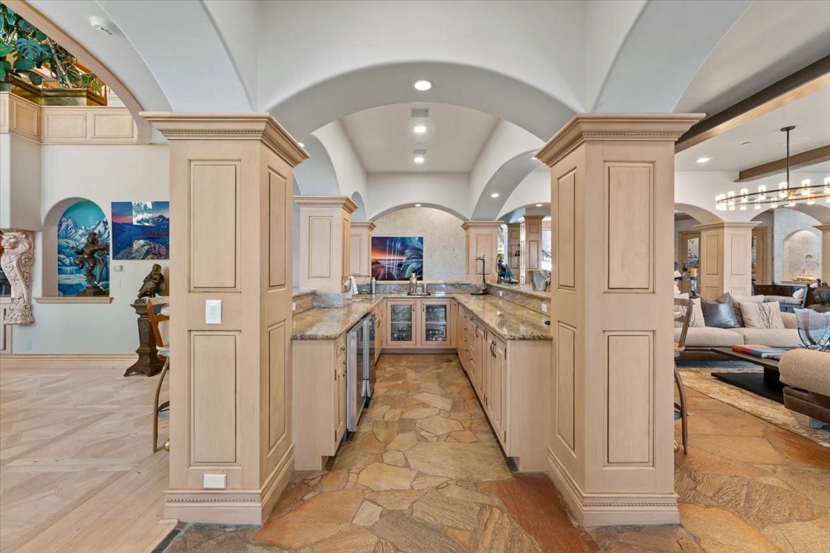 Bar with granite countertops, a sink, wine refrigerator, ice maker, and generous cabinetry.